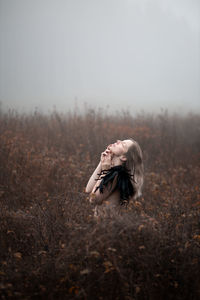 Woman standing on field during foggy weather