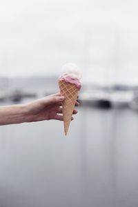 Close-up of hand holding ice cream against sea