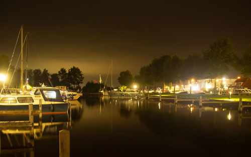 Illuminated city by river against sky at night