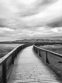 Footbridge over sea against sky