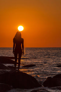 Silhouette friends standing on beach during sunset