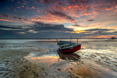 Boat on beach against dramatic sky