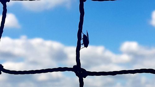 Barbed wire fence against cloudy sky