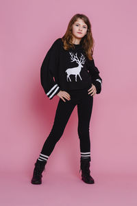 Portrait of young woman standing against pink background