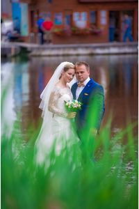 Portrait of bride and groom posing together against lake