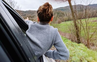 Rear view of boy leaning through car window