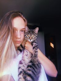 Portrait of young woman holding cat at home