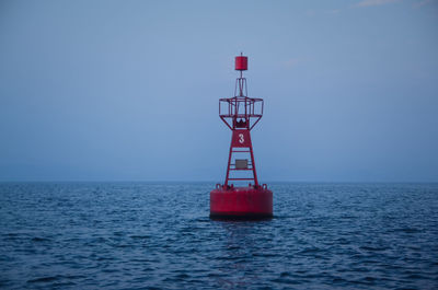 Red ship in sea against clear sky