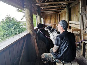 Man sitting with dogs at balcony in log cabin 