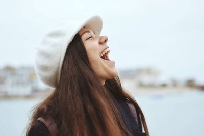 Woman laughing against sky