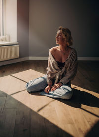 Young woman sitting on hardwood floor at home