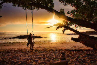 Silhouette people on beach against sky during sunset