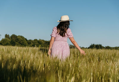 Rear view of woman touching wheat ears in field