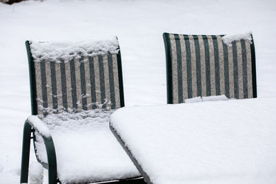 Empty chairs on snow covered field during winter