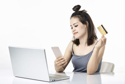 Young woman using smart phone against white background