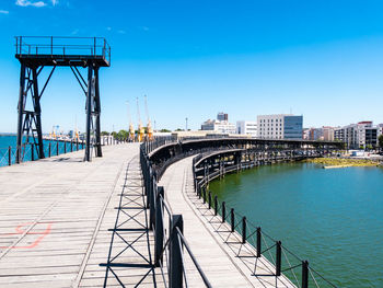 Bridge over river in city against blue sky