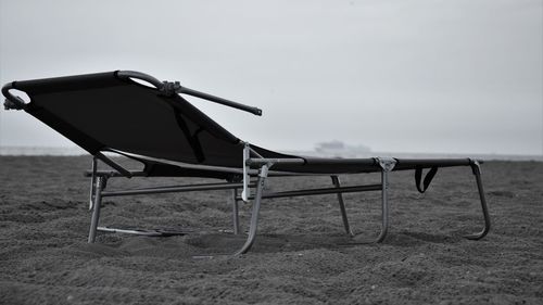 Empty chairs on beach against sky