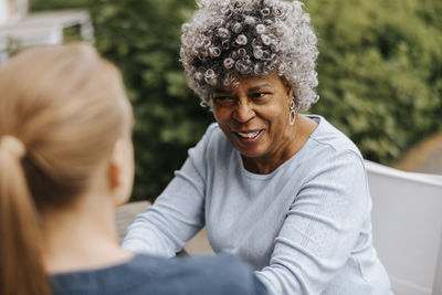 High angle view of smiling woman with curly hair talking to female nurse in back yard