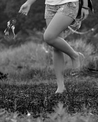 Low section of woman walking on field