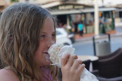 Close-up of girl eating ice cream in city