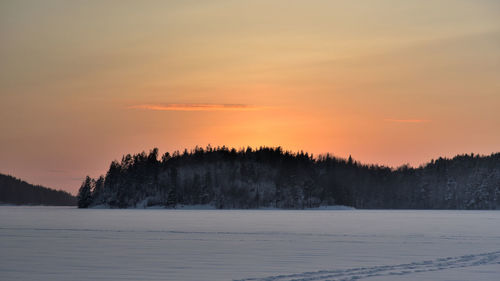 Scenic view of snow covered landscape against sky at sunset