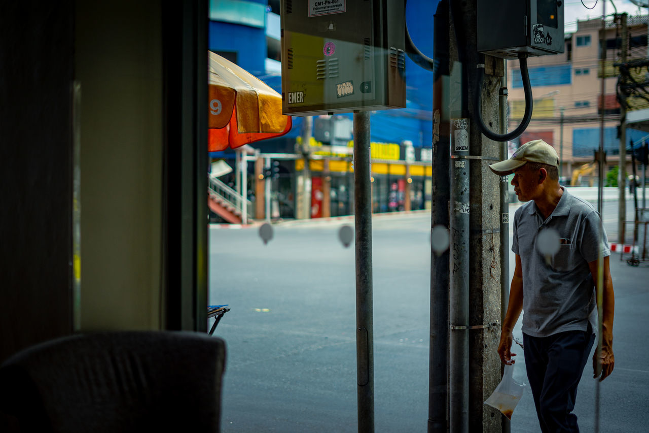 men, real people, one person, mode of transportation, transportation, three quarter length, city, land vehicle, public transportation, vehicle interior, lifestyles, glass - material, architecture, travel, clothing, standing, street, incidental people, day, outdoors