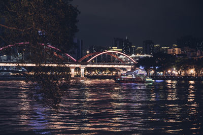 Illuminated bridge over river against sky at night