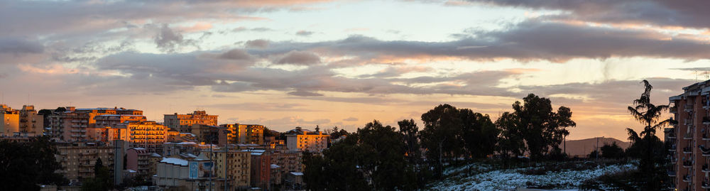 Panoramic view of buildings and trees against sky during sunset