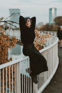 Portrait of young woman standing against railing