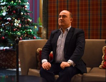 Mature man sitting on sofa at home during christmas