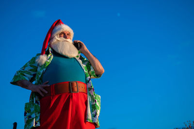 Low angle view of man standing against blue sky