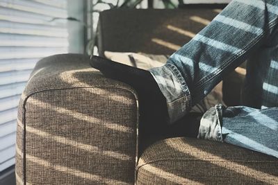 Low section of man wearing sock relaxing on sofa at home