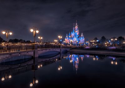 Illuminated bridge over river in city at night