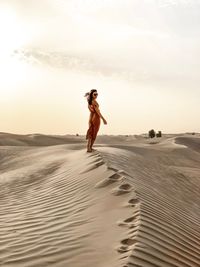 Woman standing on sand at beach against sky