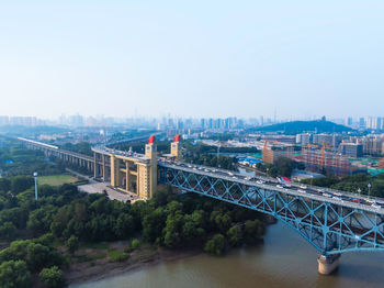 Bridge over river amidst buildings in city against clear sky