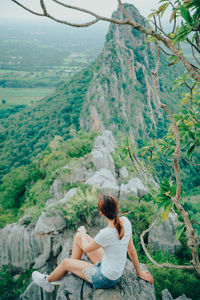 Rear view of woman sitting on mountain