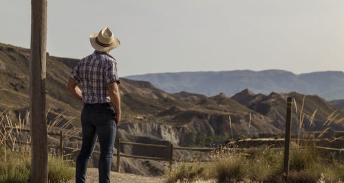 Rear view of adult man in sun hat and shirt in desert. almeria, spain