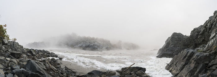 Rock formations at shore against clear sky