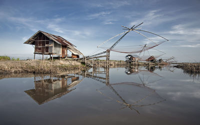 Commercial fishing net over lake against sky