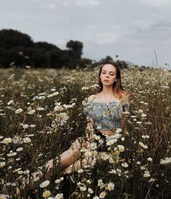 Woman with eyes closed by plants against sky