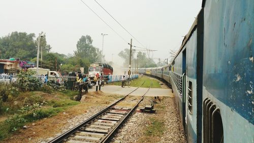 Train by railroad crossing against sky