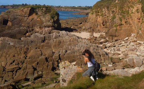 Full length of woman sitting on rock