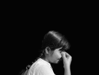 Close-up portrait of a young woman against black background