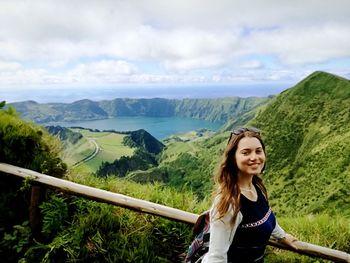 Portrait of smiling hiker standing against cloudy sky