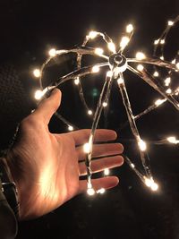 Close-up of hand holding illuminated lights at night