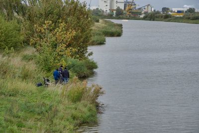 Rear view of men by river amidst trees