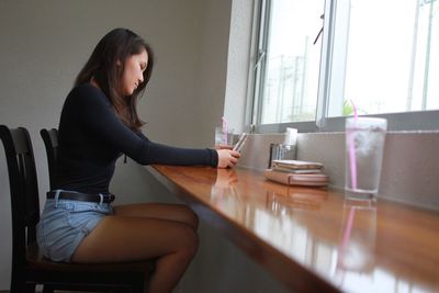Side view of woman using laptop on table at home