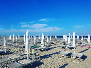 Chairs on beach against blue sky