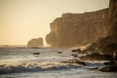 Rock formations on beach against clear sky