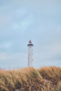 Lighthouse by sea against sky